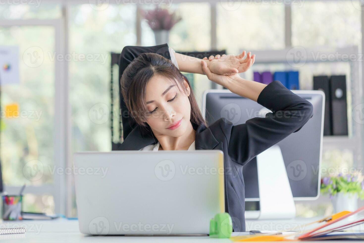 Office syndrome, Asian woman doing stretch exercise stretching her arms in work time, Female officer feeling tired and fatigue stretching to relax photo