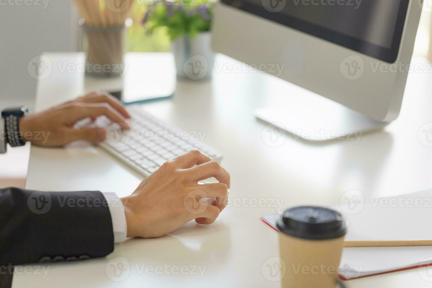 Close-up of male hand clicking wireless digital mouse working with desktop computer at office desk photo