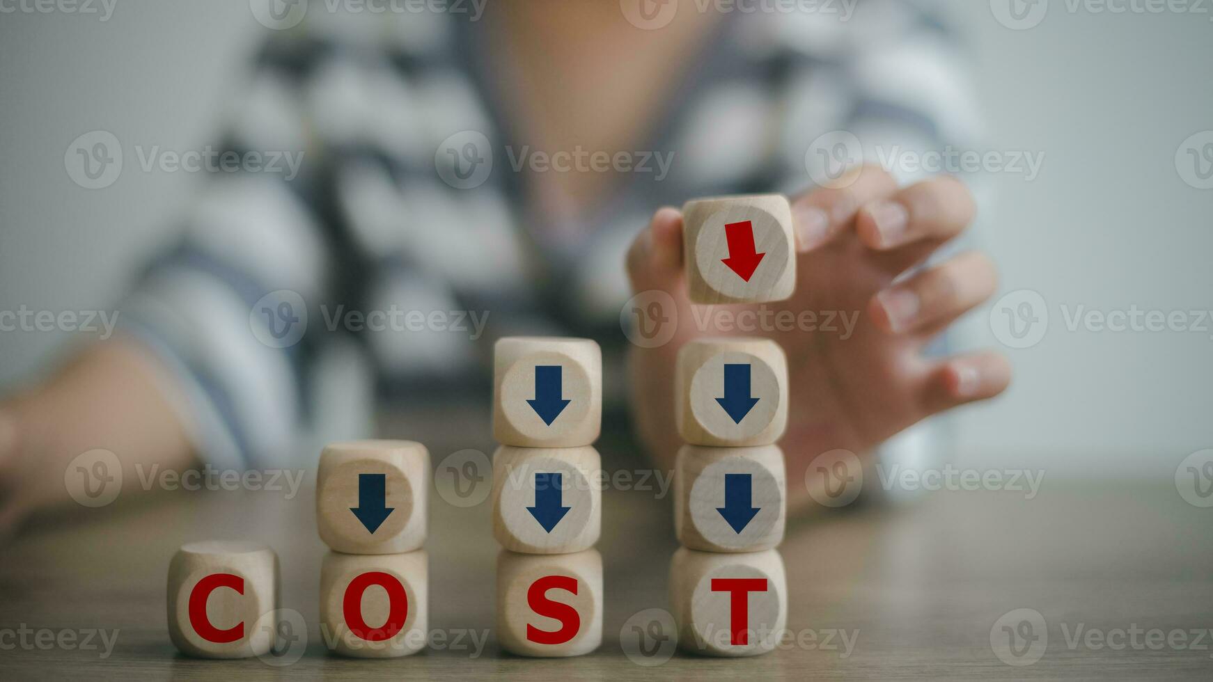 Hand puts wooden cube with words cost and green down arrows. Optimize manufacturing management. Decreasing company expenses to maximize profits. Cost reduction concept. photo