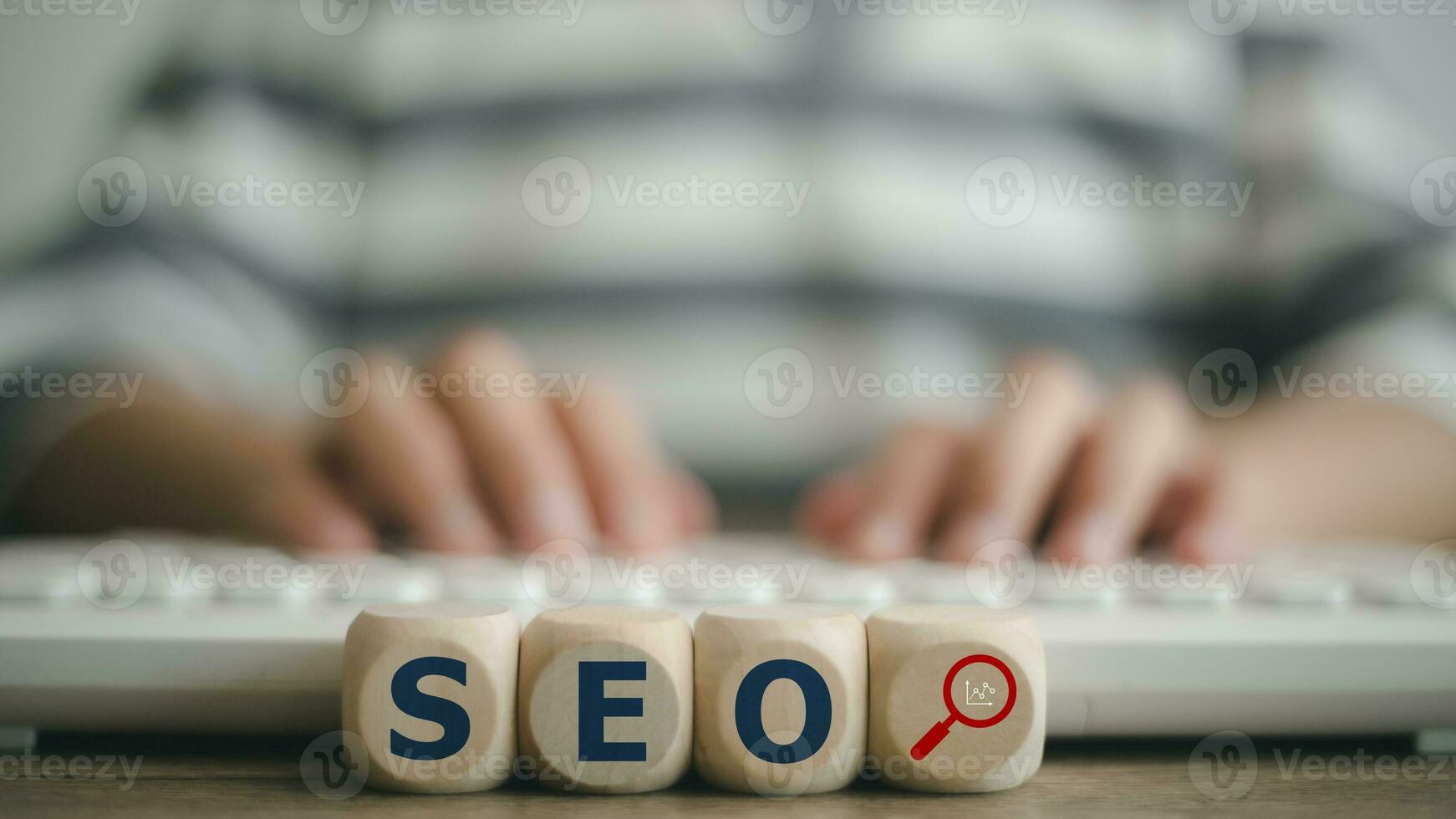 Search Engine Optimization SEO concept on wooden cubes with a woman using a computer keyboard. photo
