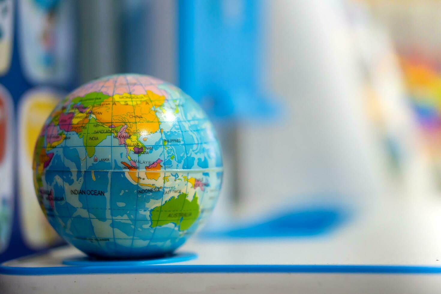 A blue toy globe rests on a student's desk. photo