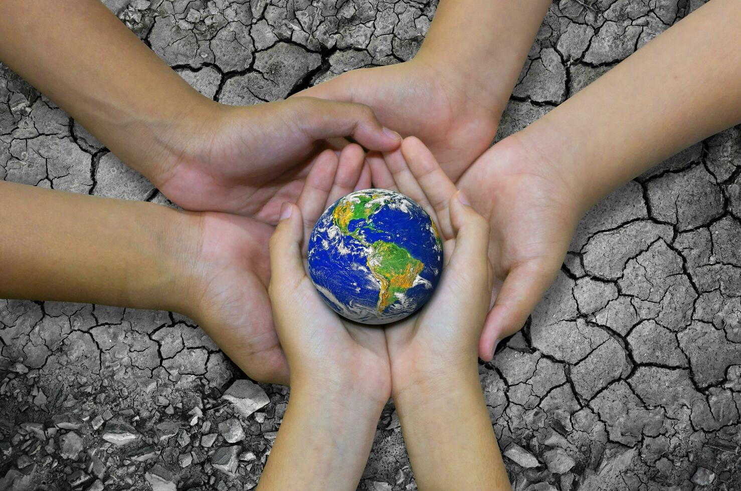 Earth planet in asian Children hand isolated on Ground arid barren photo