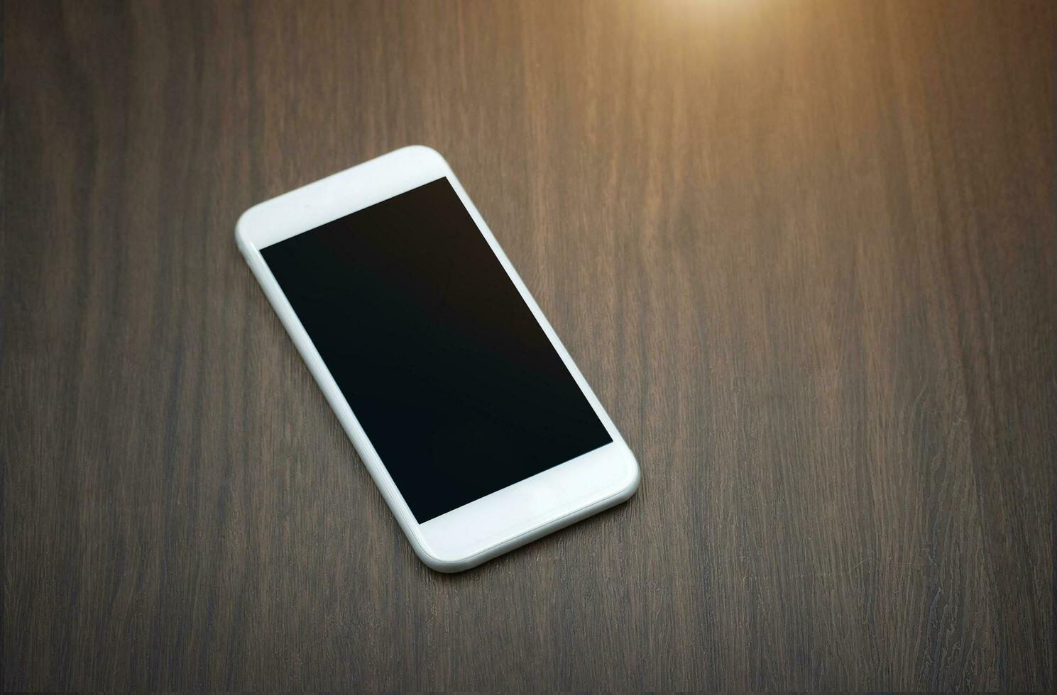 Smart phone with blank screen lying on wooden table photo