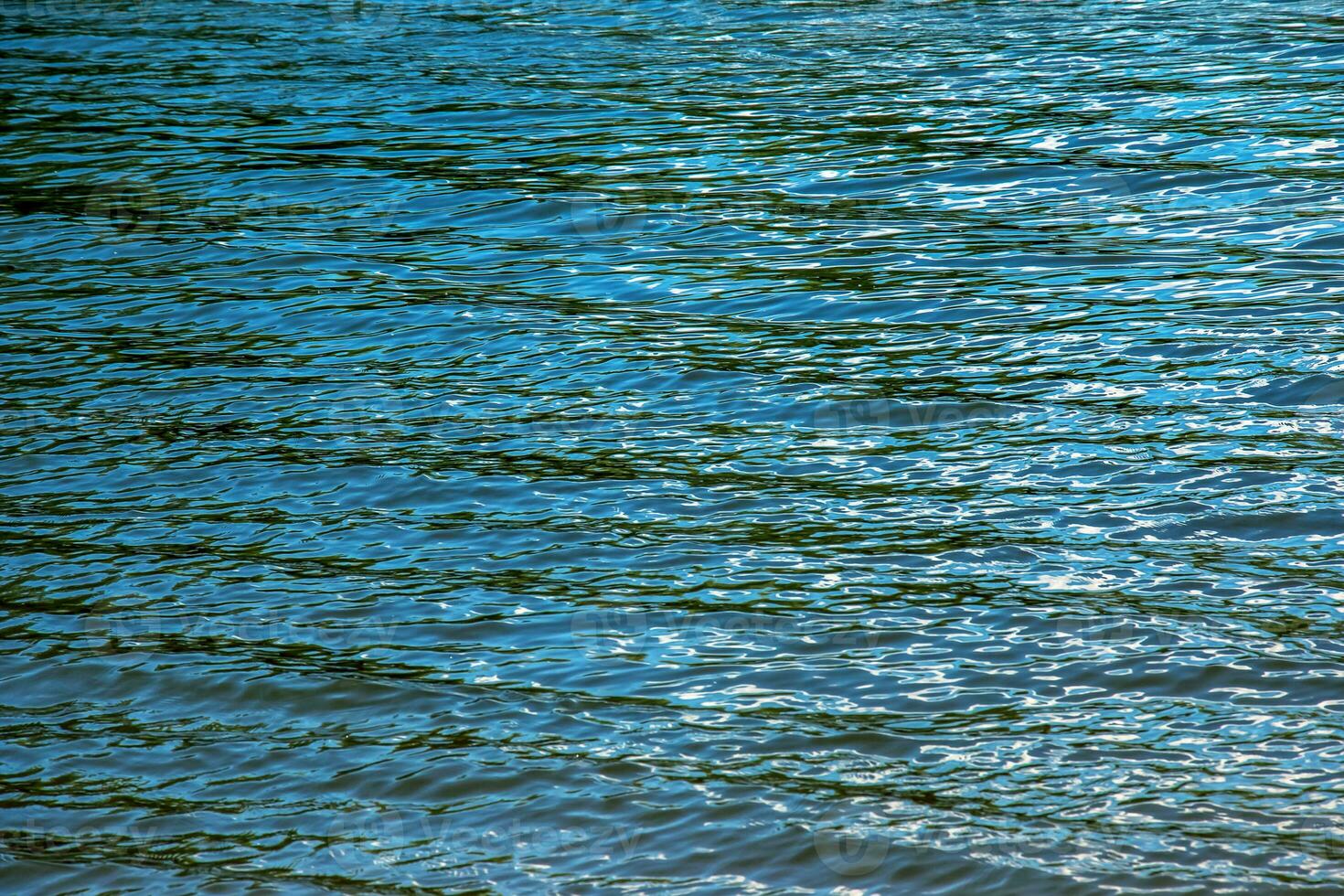 Water ripple texture background. Wavy water surface during sunset, golden light reflecting in the water. photo