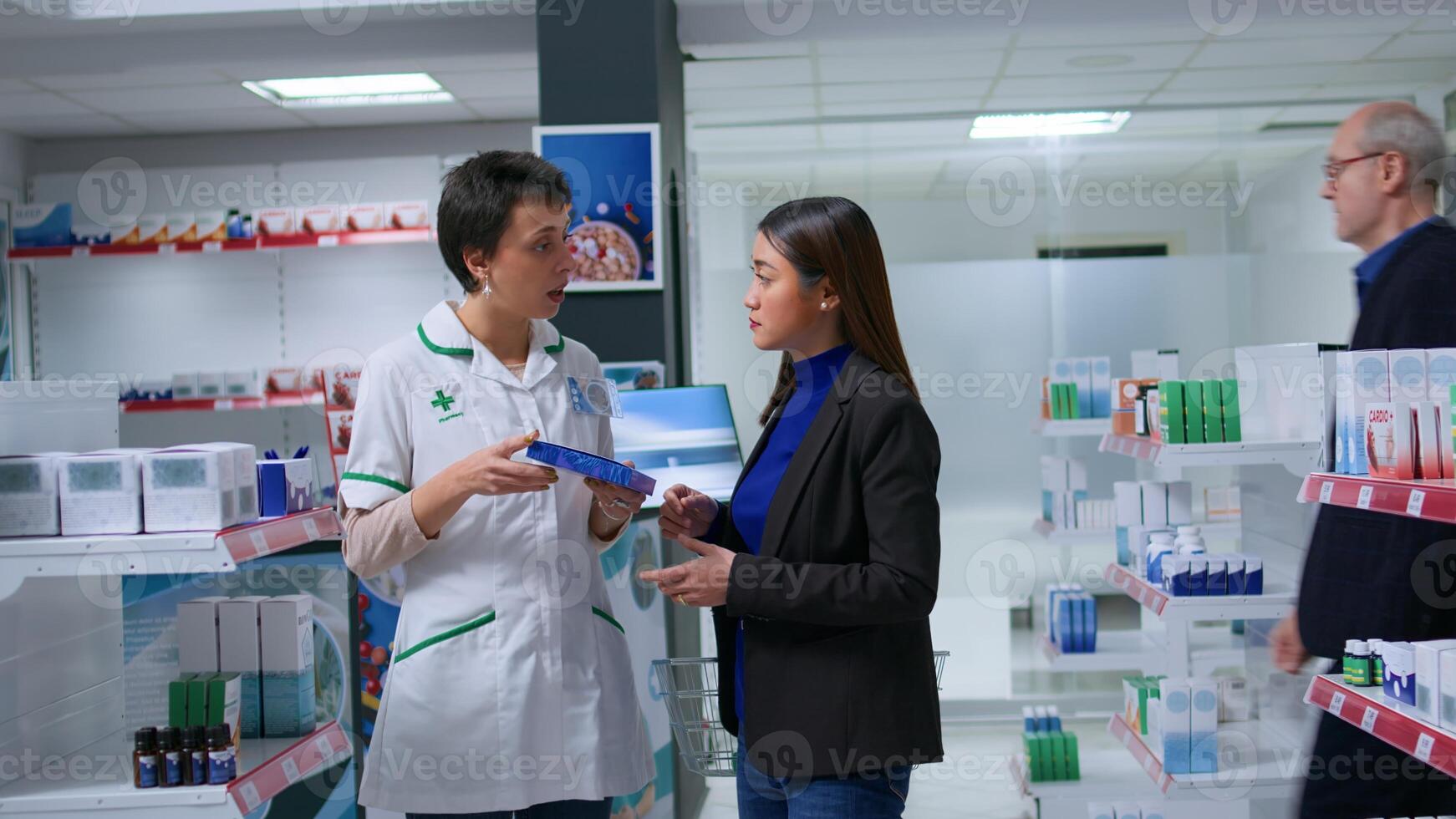 Healthcare specialist in apothecary with patient prescribing her melationin pills to cure sleeping issues. Asian customer receiving insomnia medical product from chemist store worker photo