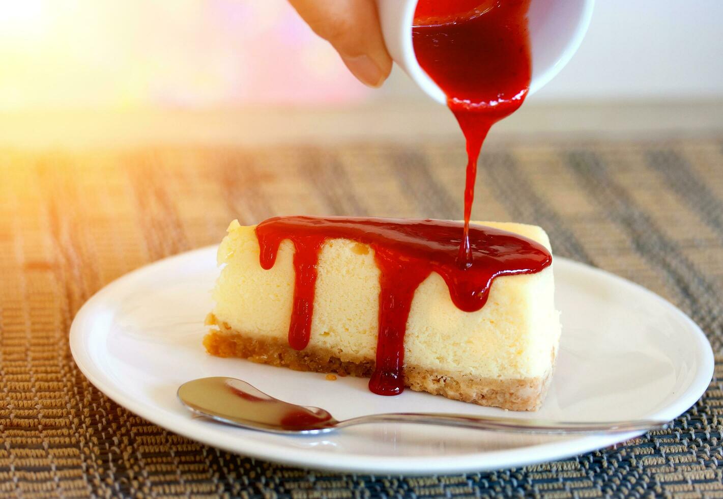 Pour strawberry sauce into cheesecake photo