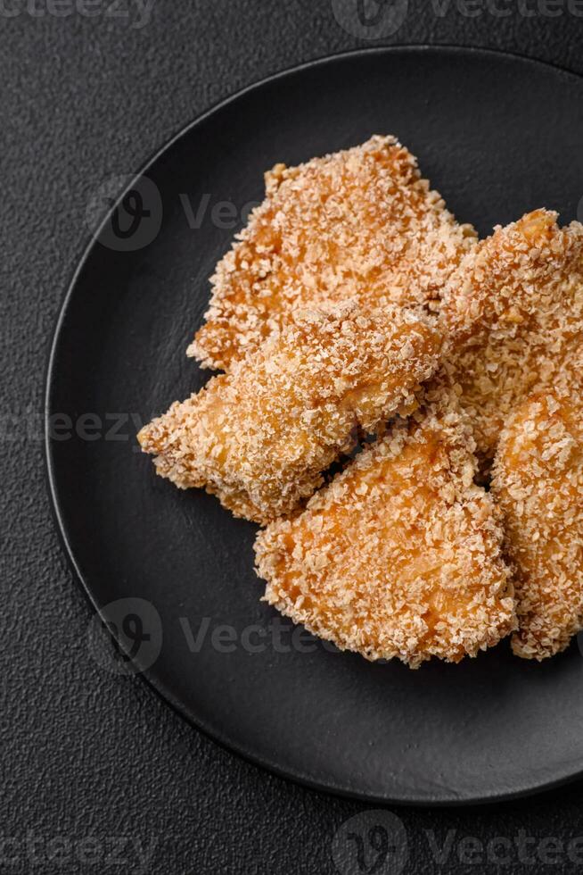 Delicious fresh crispy chicken nuggets on a dark concrete background photo