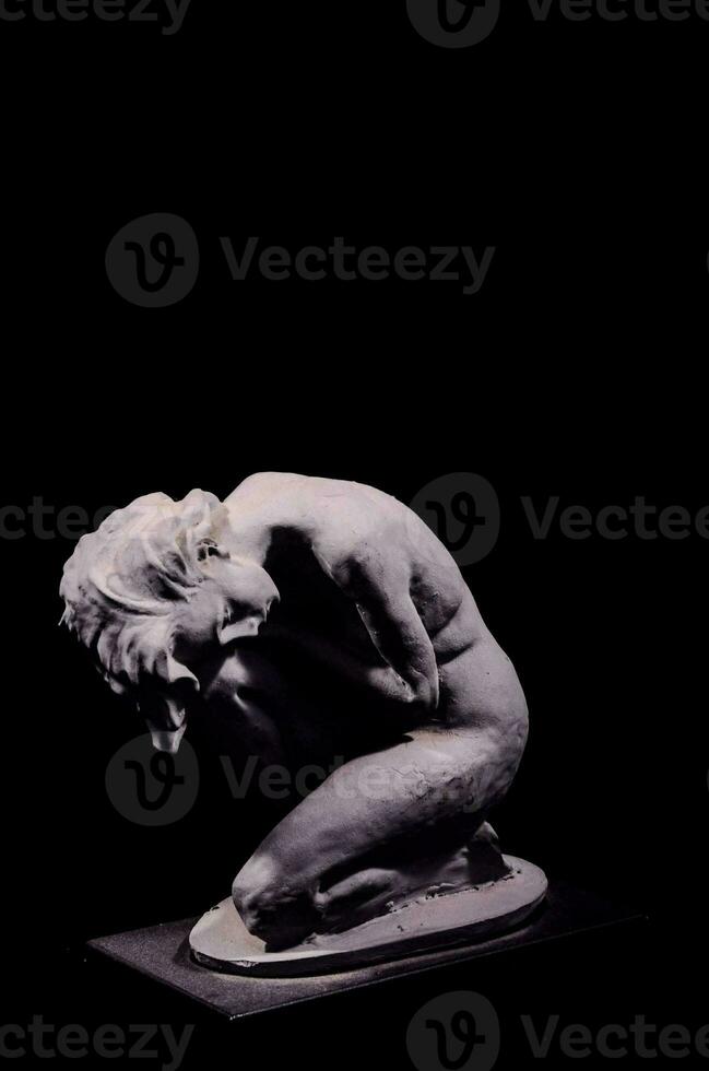 a sculpture of a woman kneeling on a black background photo