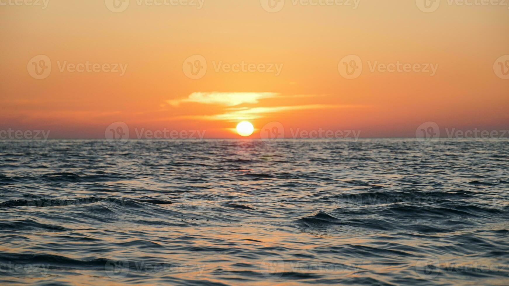 Bright sunset with large yellow sun under the sea surface, Panorama of sea sunset, seascape. Sunset over the sea horizon photo