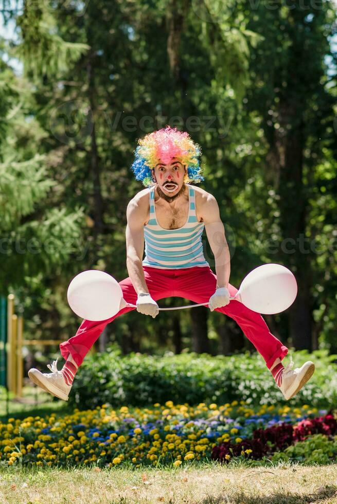 Mime jumps in the park with balloons. Clown in the air shows pantomime on the street. photo