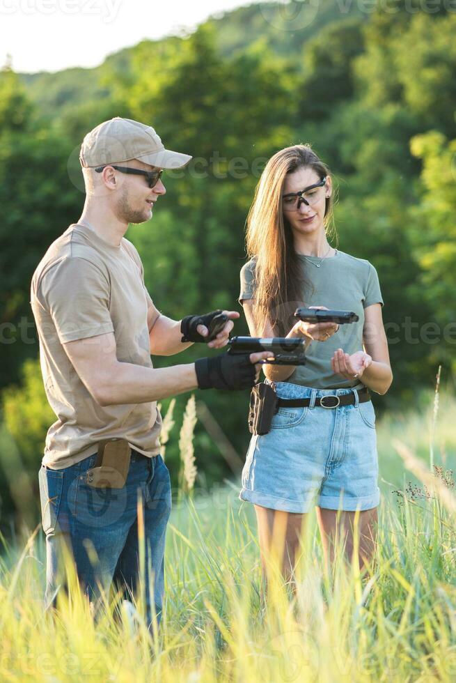 un masculino armas instructor enseña un niña cómo a correctamente disparar un pistola foto