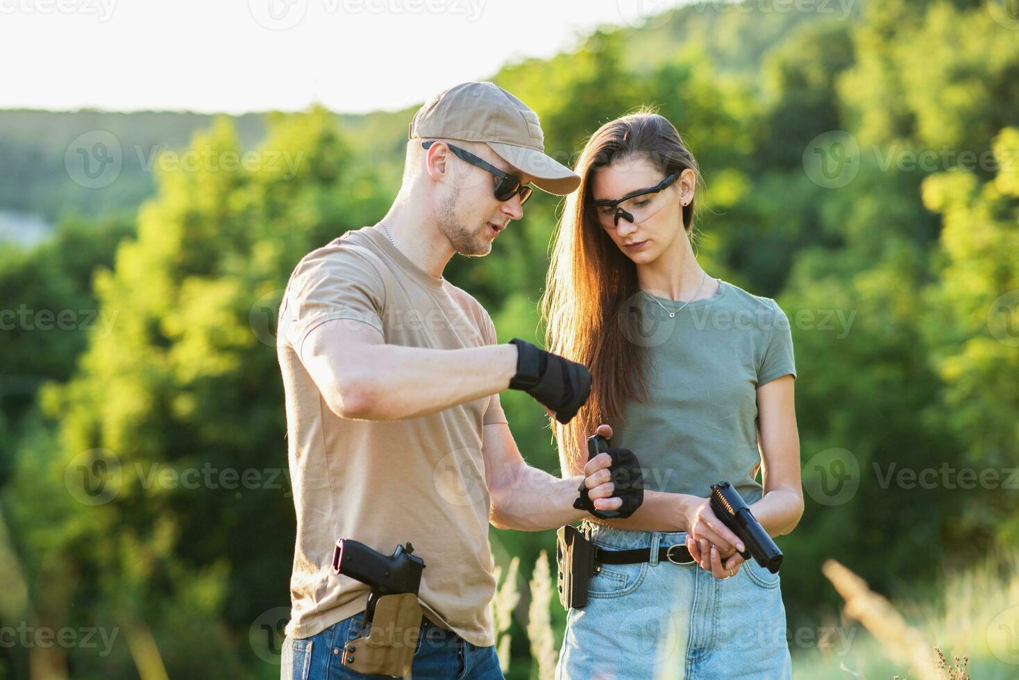 A girl learns to shoot a pistol with an instructor at the training ground photo