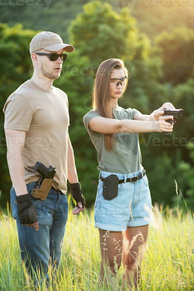 A girl learns to shoot a pistol with an instructor at the training ground photo