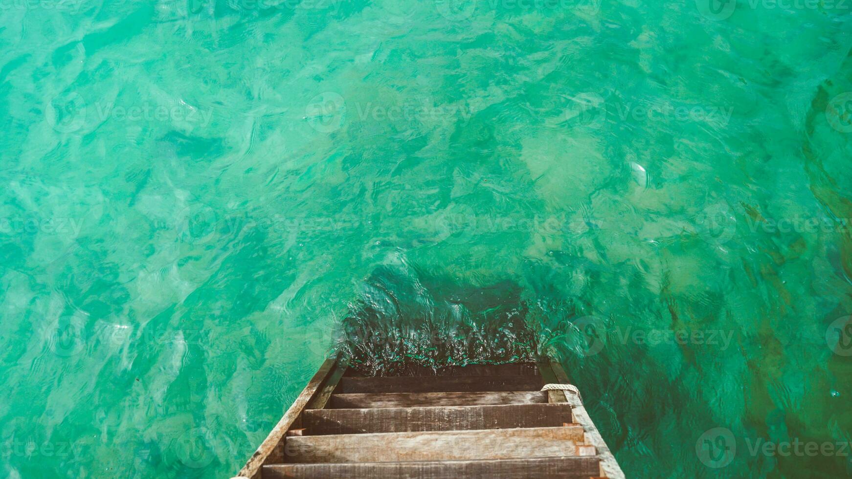 vacío muelles. de madera escalera yendo dentro el mar con pequeño olas y turquesa agua. foto