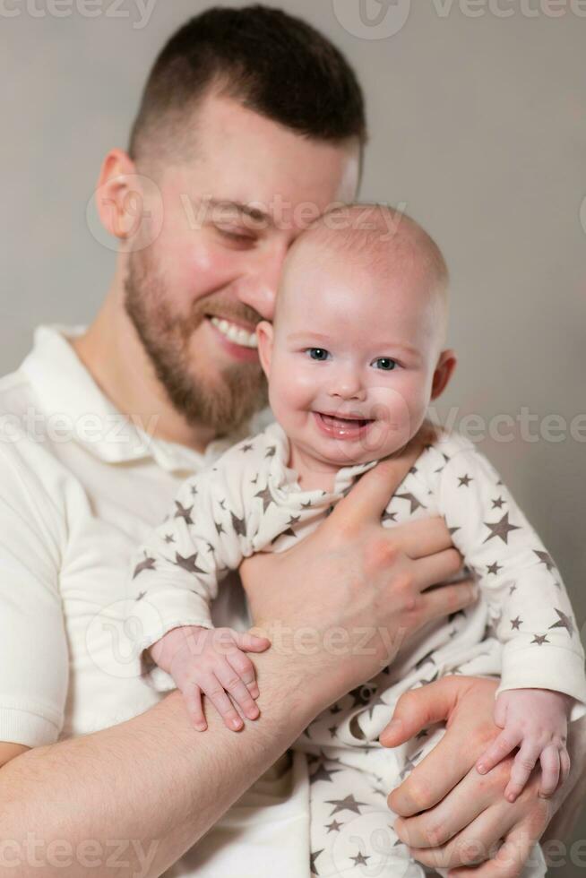 papá sostiene su hijo en su brazos. padre obras de teatro con recién nacido bebé a hogar. foto