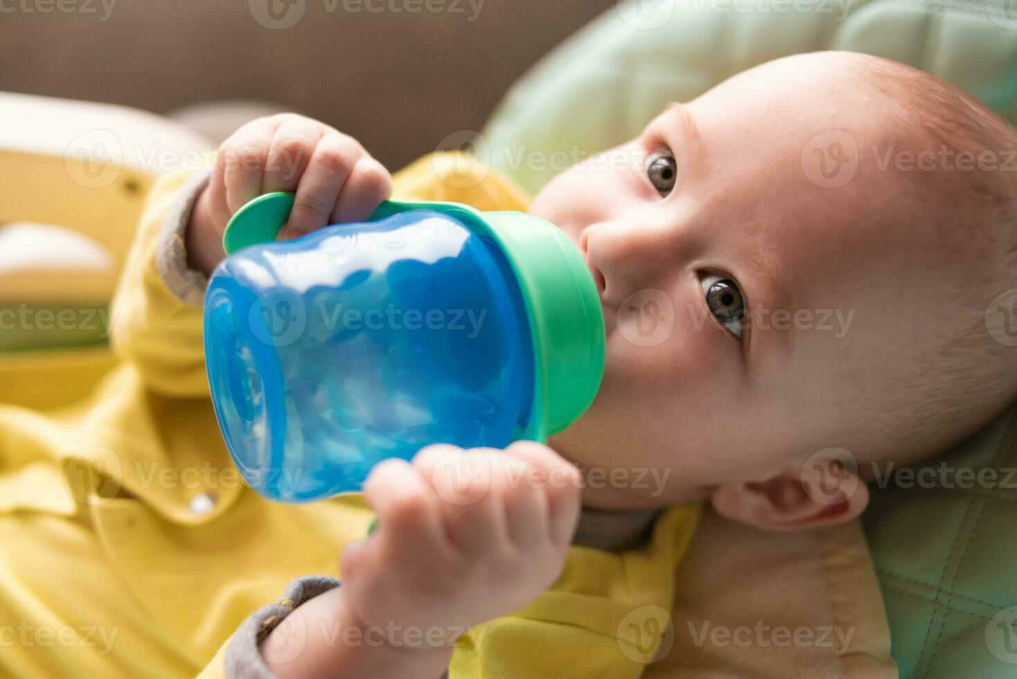 el bebé bebidas agua desde un botella. foto