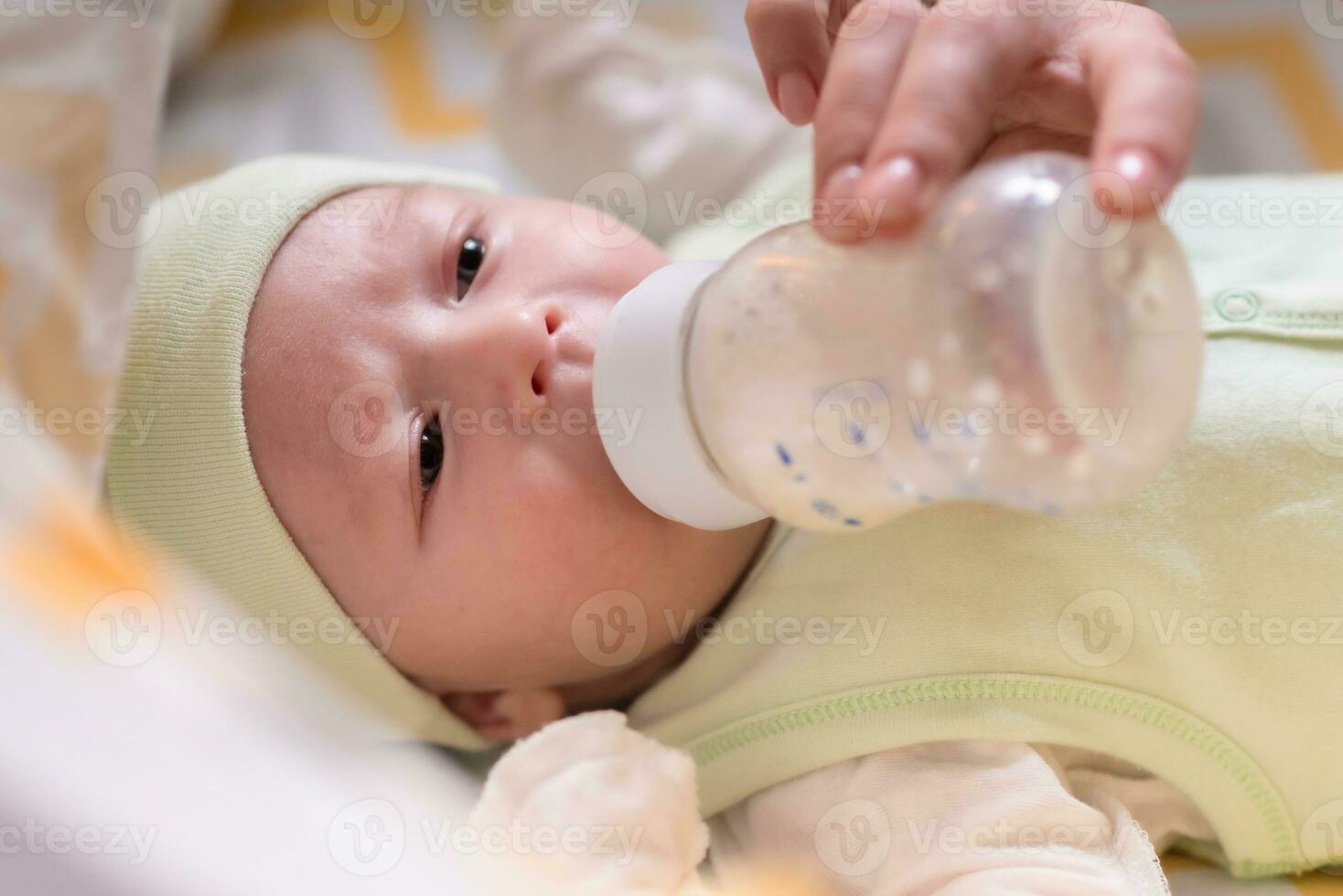 young mother feeds her baby milk from a bottle photo