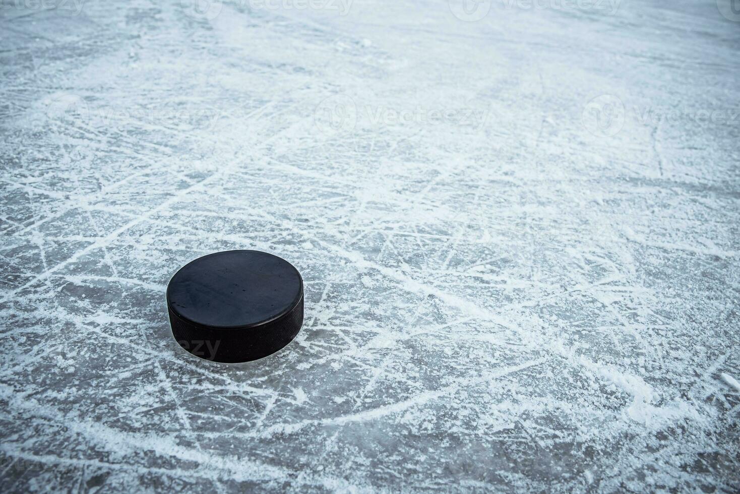 black hockey puck lies on ice at stadium photo