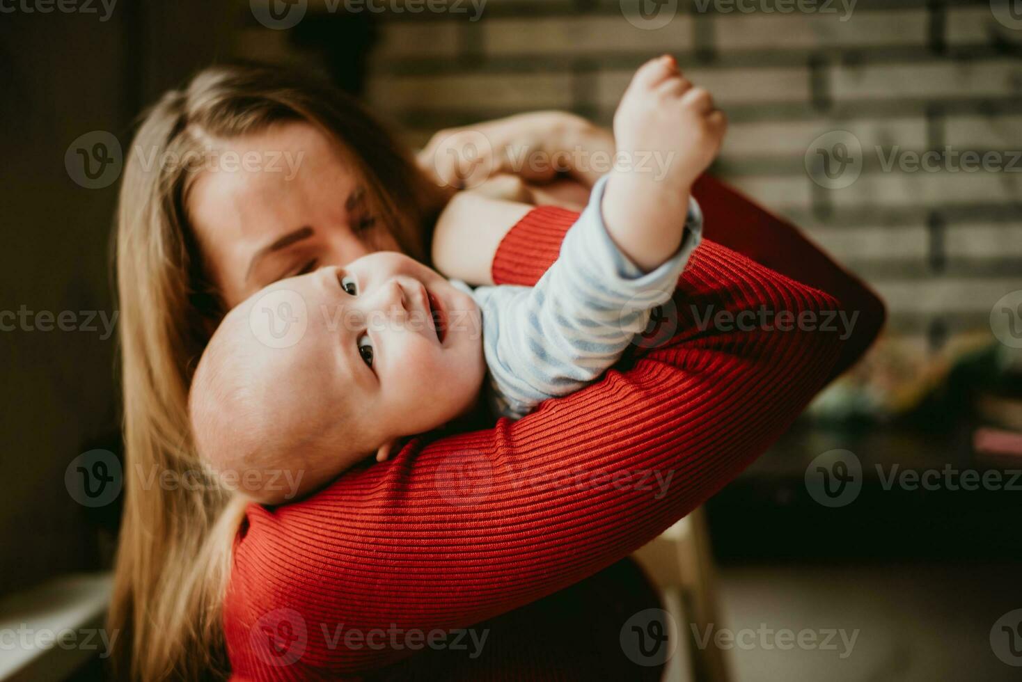 un madre sostiene un bebé en su brazos. un mamá Besos un niño. un mujer abrazos su niño pequeño. un niña tiene divertido y se regocija con el niño. foto