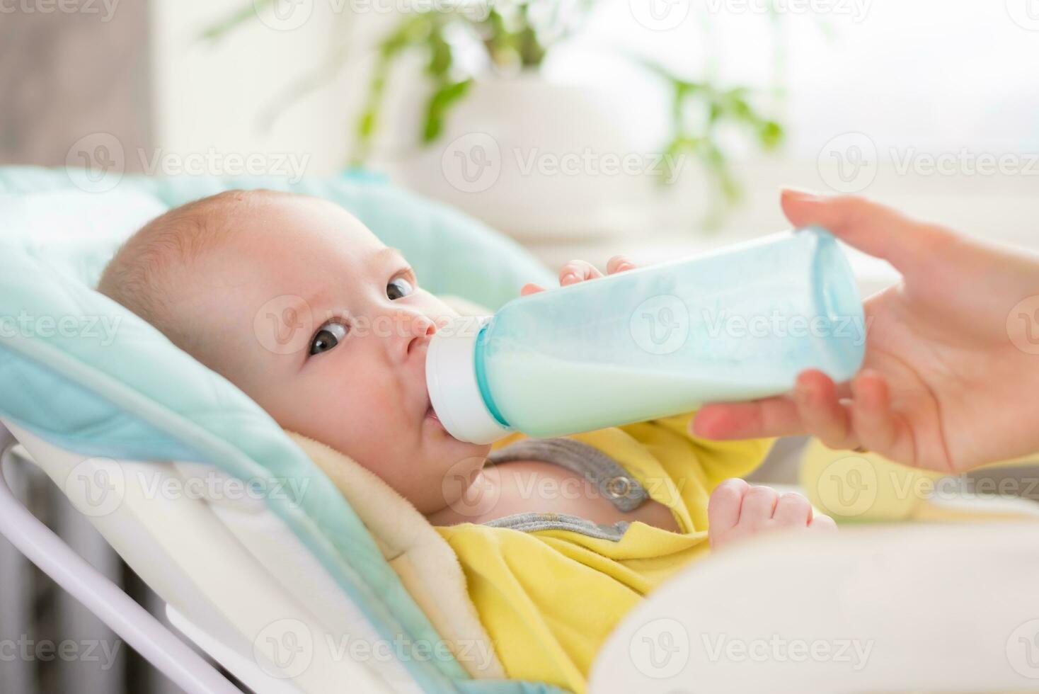 madre alimenta el bebé. el niñito bebidas Leche desde un botella . foto