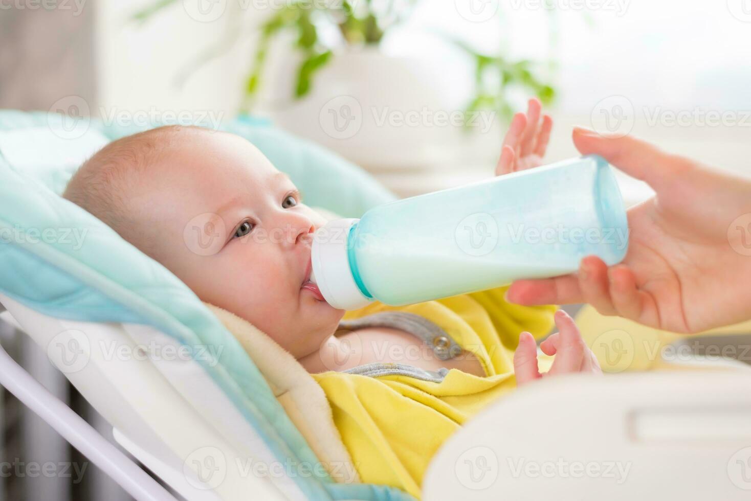 madre alimenta el bebé. el niñito bebidas Leche desde un botella . foto