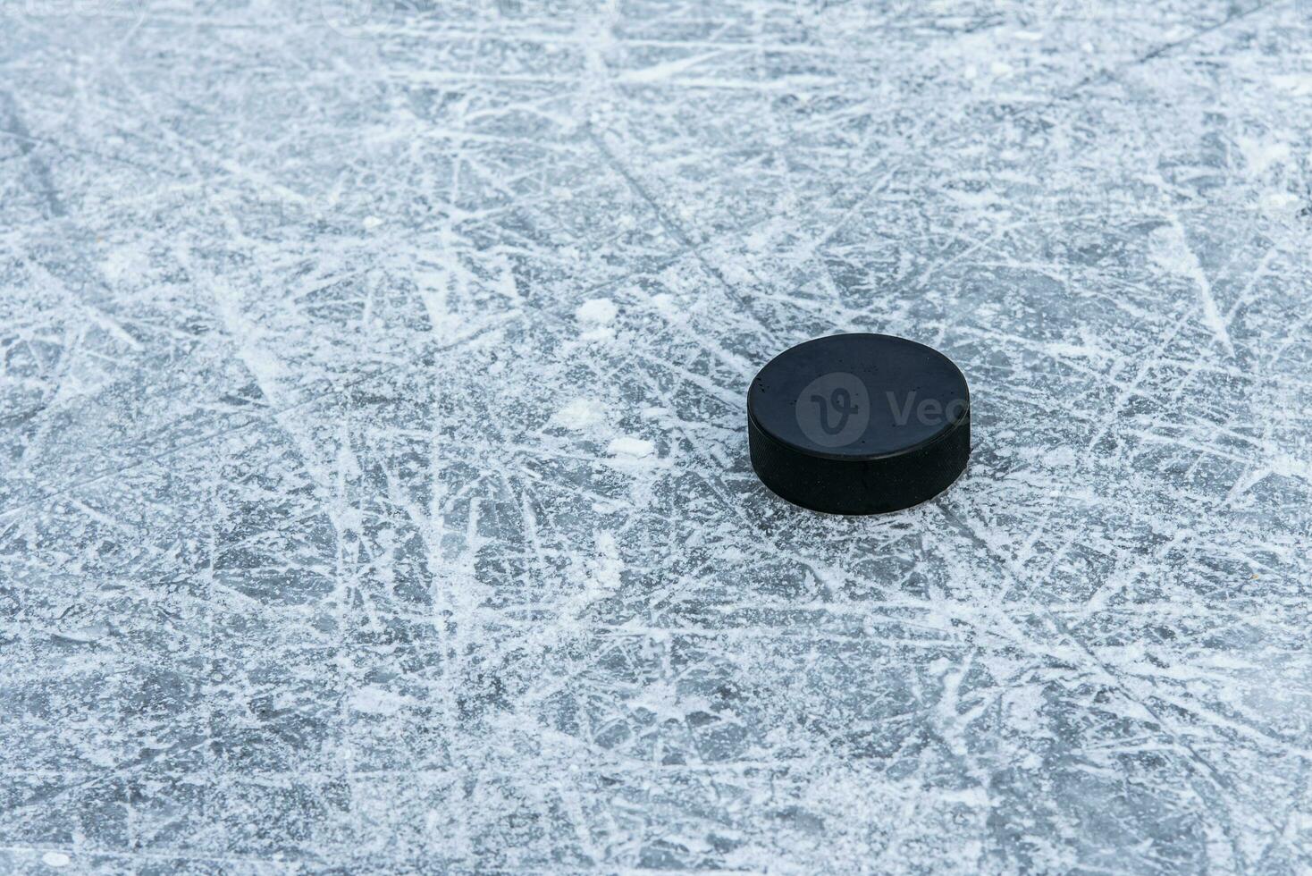 black hockey puck lies on ice at stadium photo