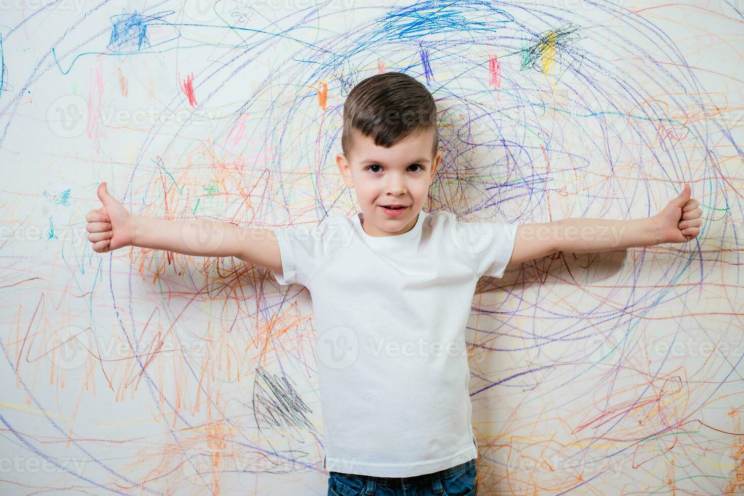 The child is engaged in creative work at home. A boy stands by the wall painted by him photo