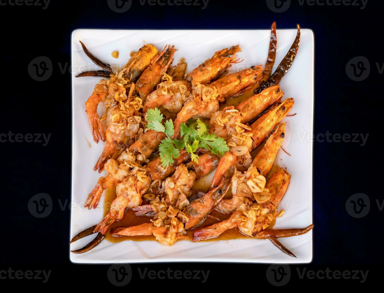 Crispy prawns in tamarind sauce in  white square dish, sprinkle with glaze and top with fried shallots and coriander. It has perfect balance of crispy, spicy, and sweet flavors. photo