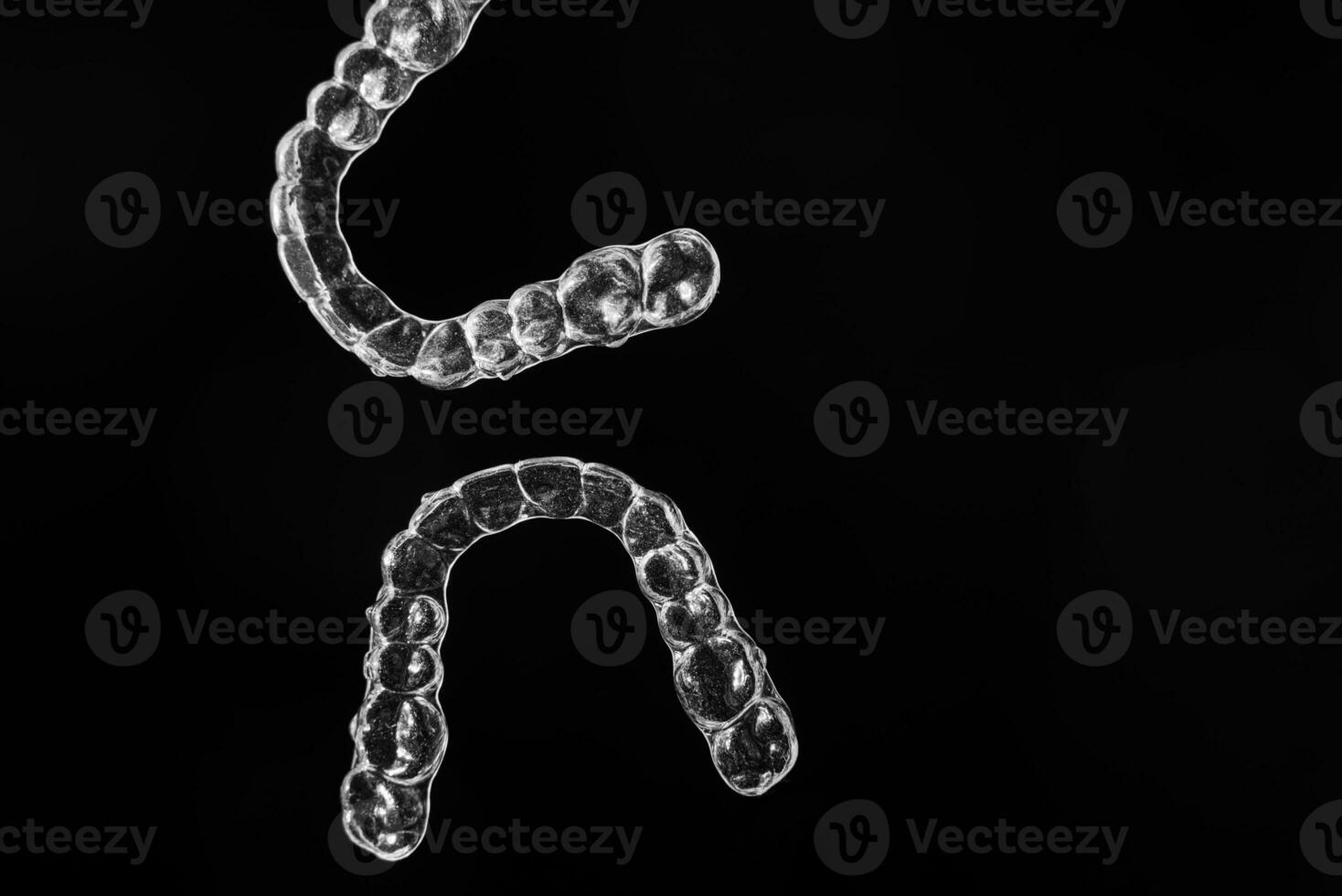 Invisible aligner teeth retainers on a black background photo