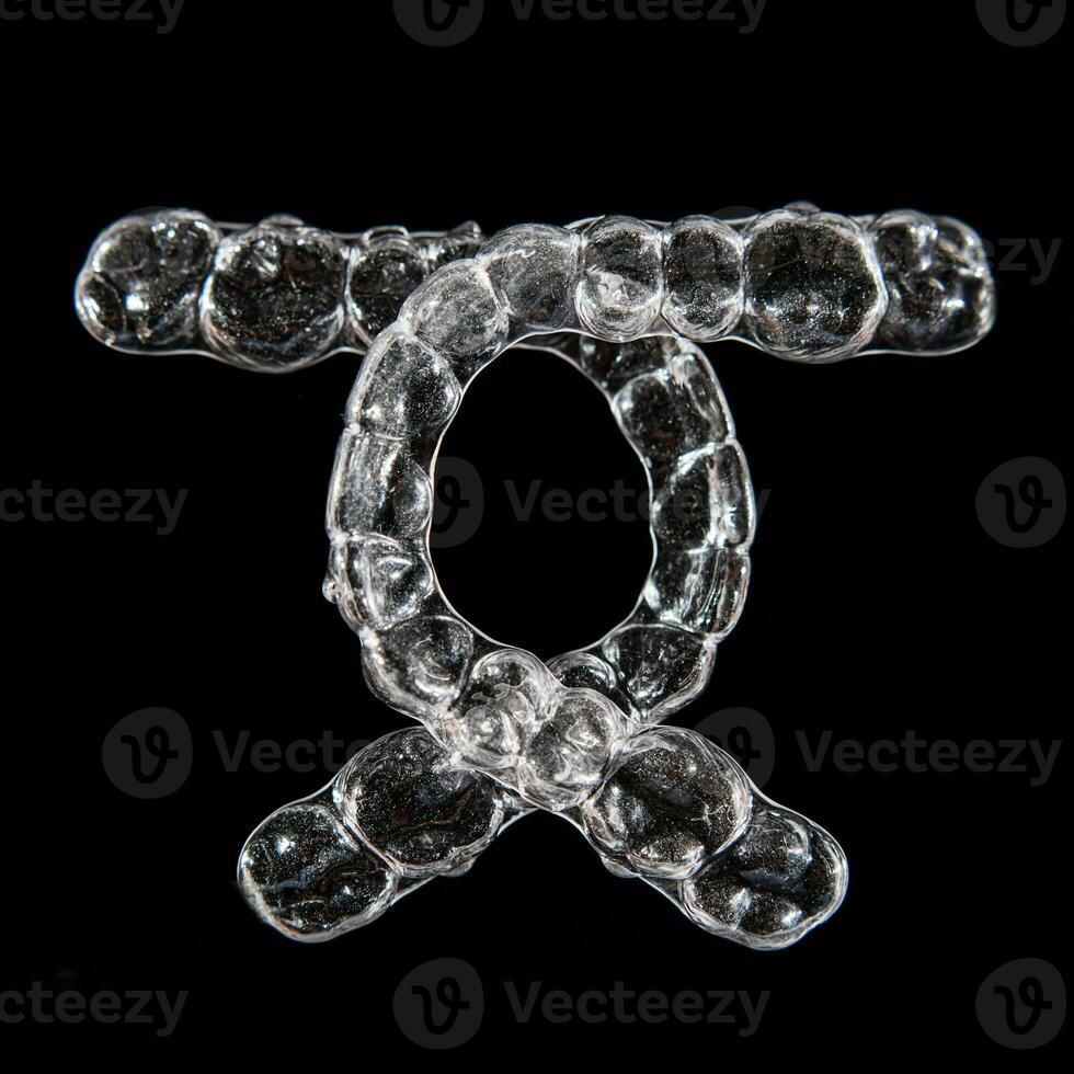 Invisible aligner teeth retainers on a black background photo