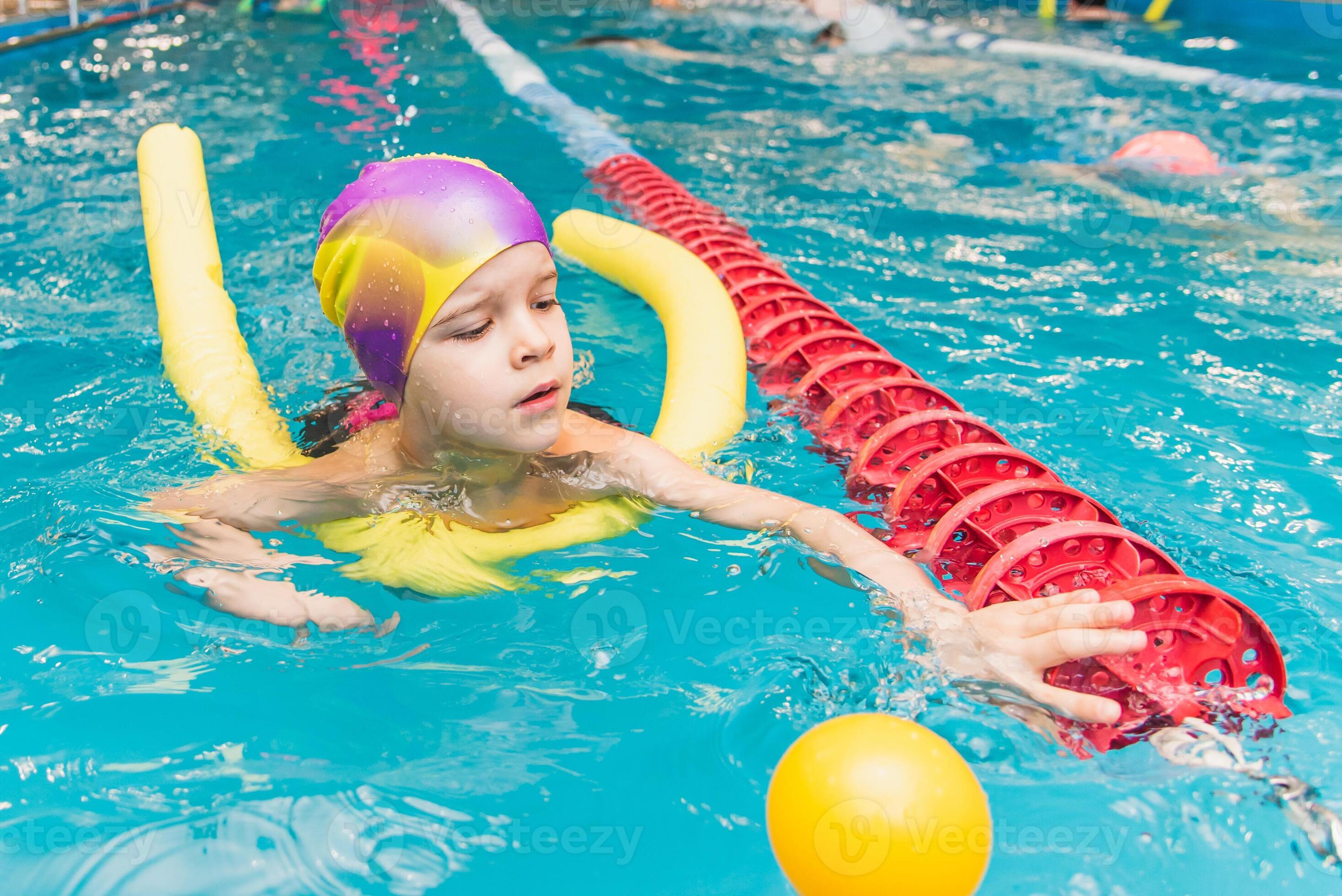 A little boy with a life jacket on his chest learns to swim in an indoor pool. 34733696 Stock