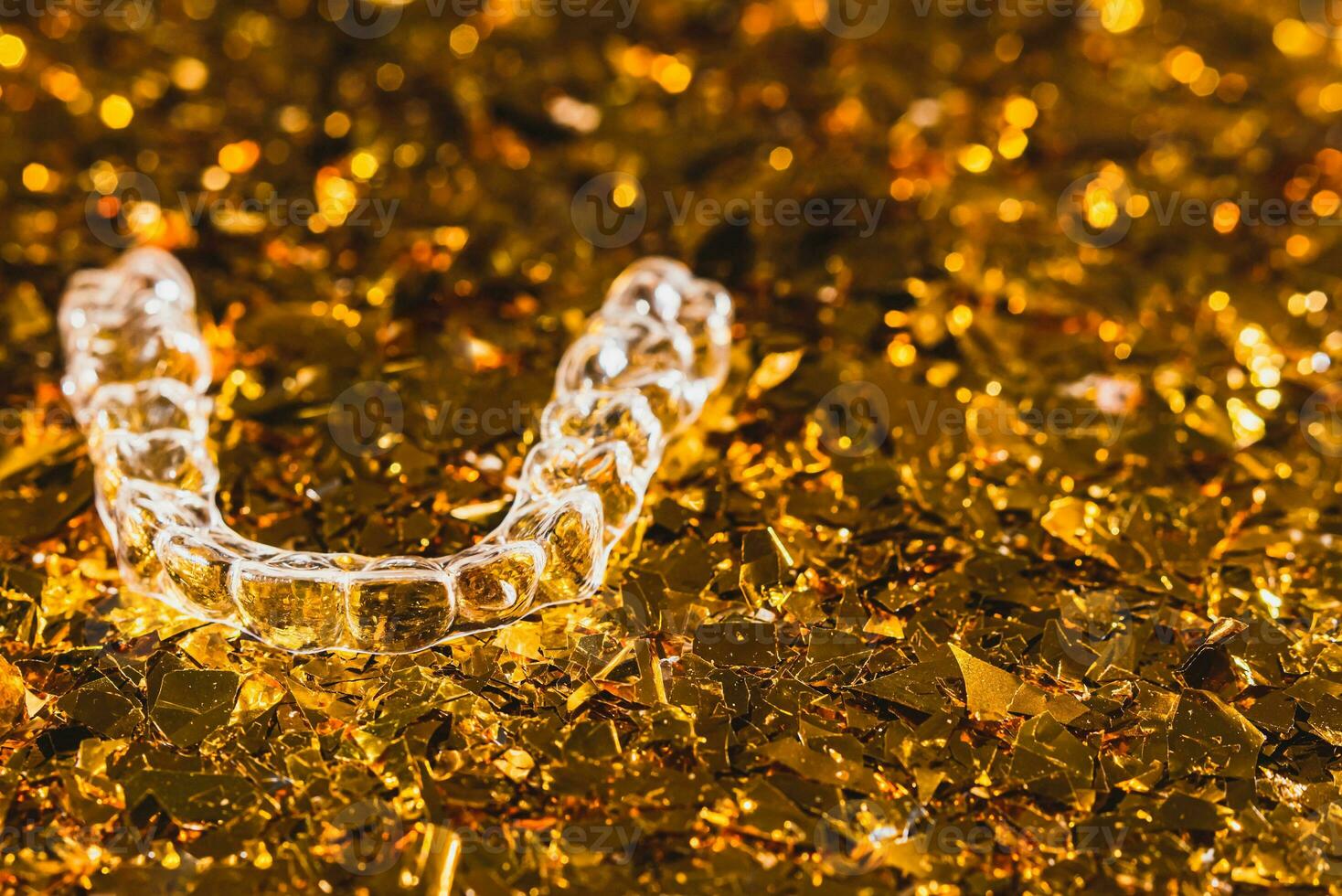 Invisible aligner teeth retainers on a gold background photo