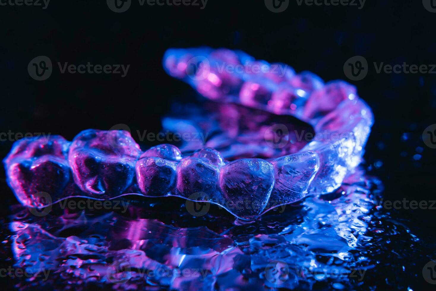 transparente alineadores, diente retenedores mentira en un espejo con agua gotas en un negro antecedentes foto