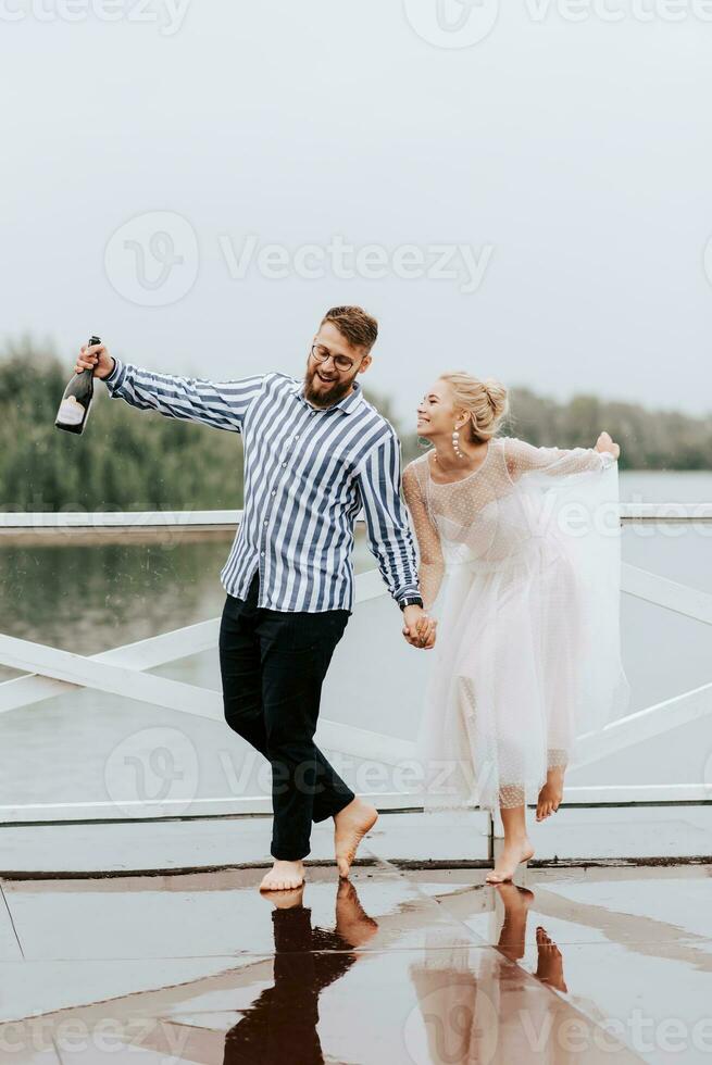 Beautiful just married dance barefoot and have fun on the pier by the water. photo