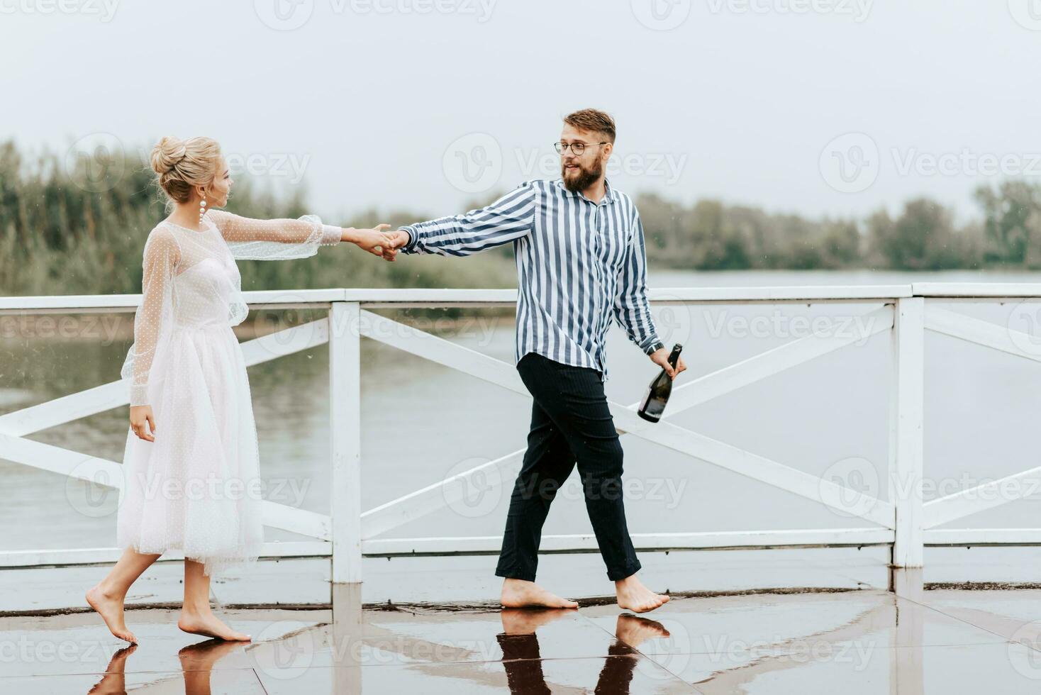 joven recién casados danza descalzo y tener divertido en el muelle por el agua. foto