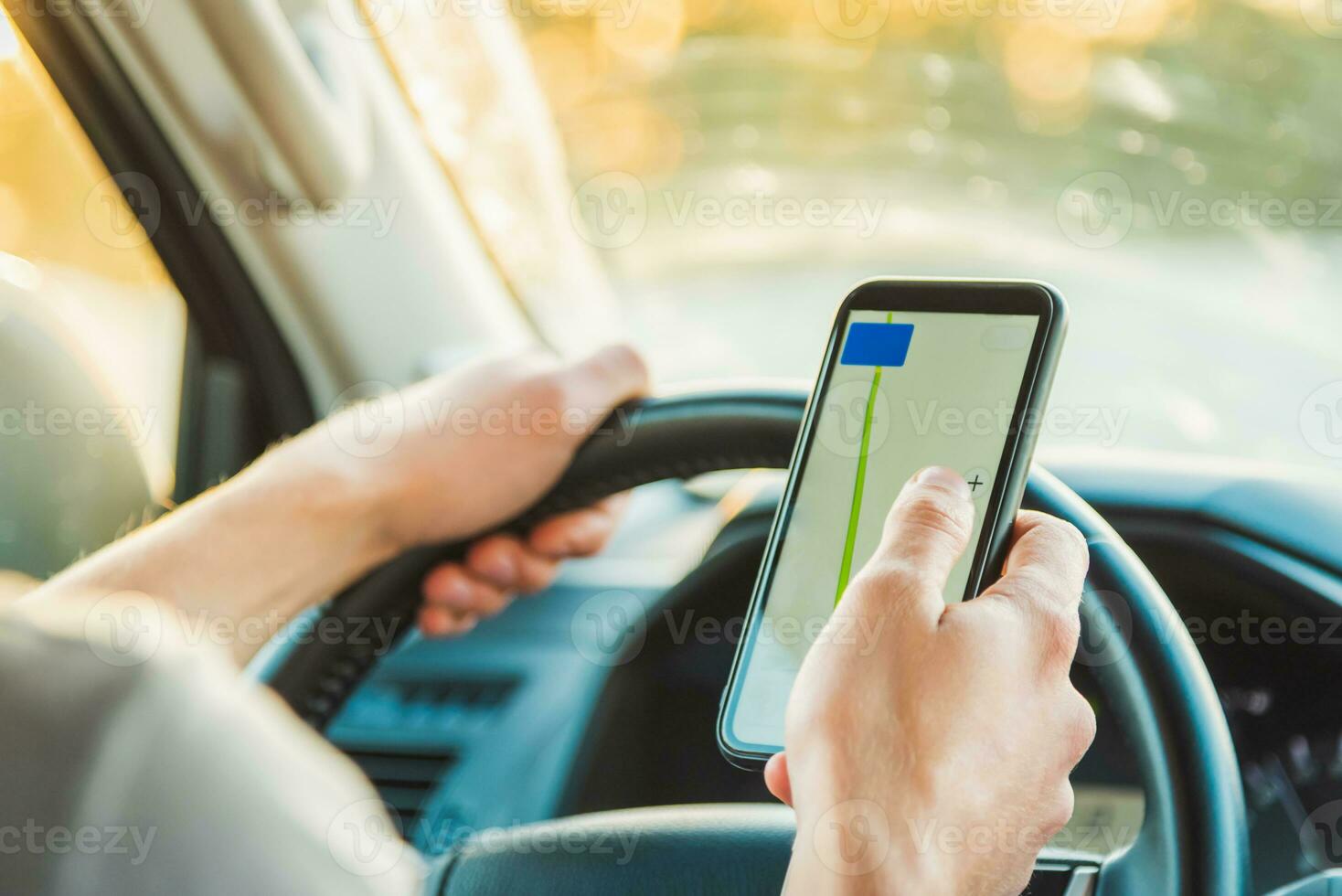 A tourist is sitting in a car and looking for the road in the Navigator app on a Sunny day photo