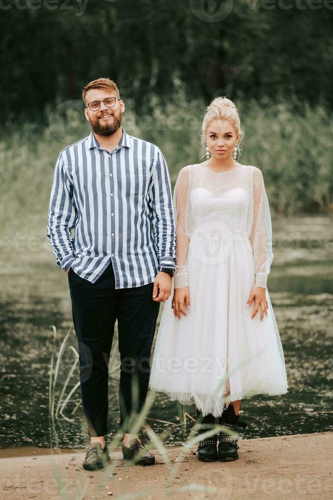Young newlyweds stand on the background of the river and pose. photo