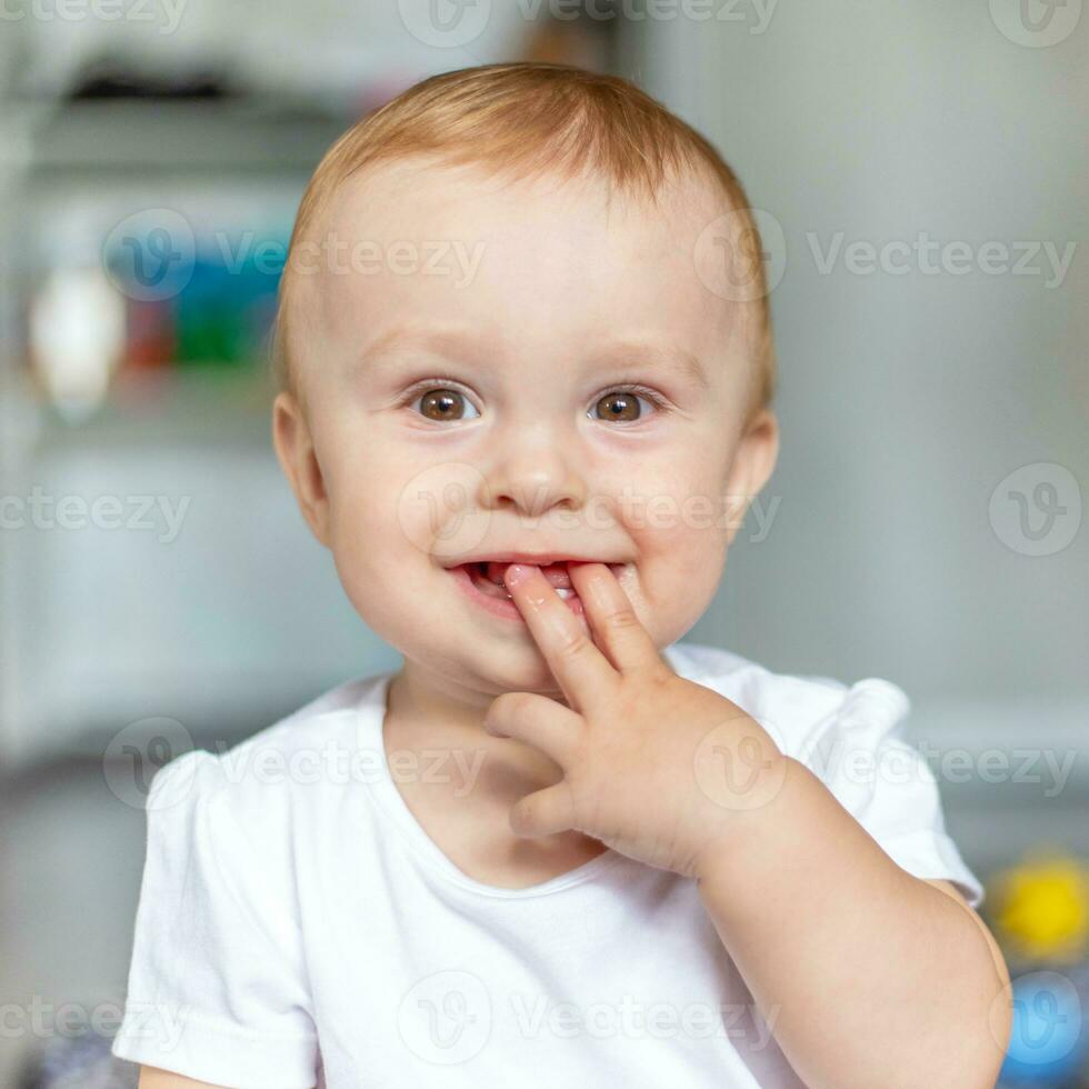 Happy child laughing and sucking fingers while sitting on the floor photo