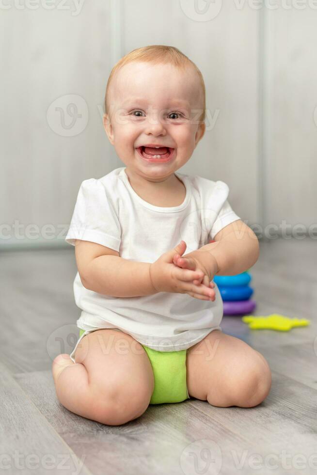 Cute baby laughing while sitting on the floor photo