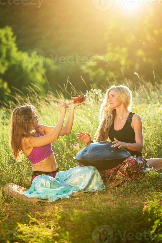 joven mujer jugar y canta en el musical instrumento pan de mano. práctica meditación a puesta de sol foto