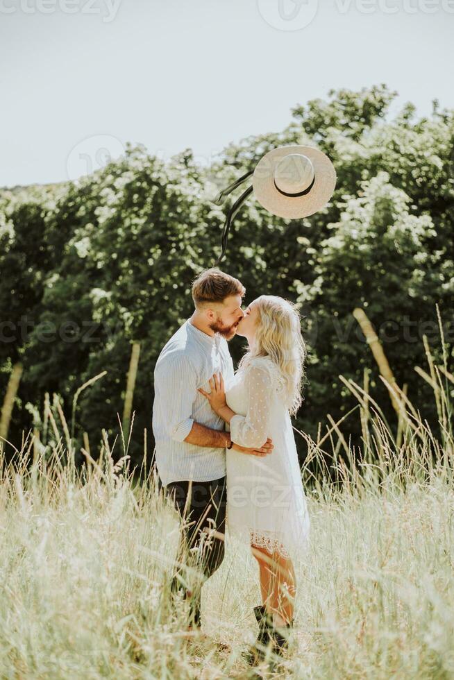 Happy and loving couple kissing and throwing hat up in summer photo