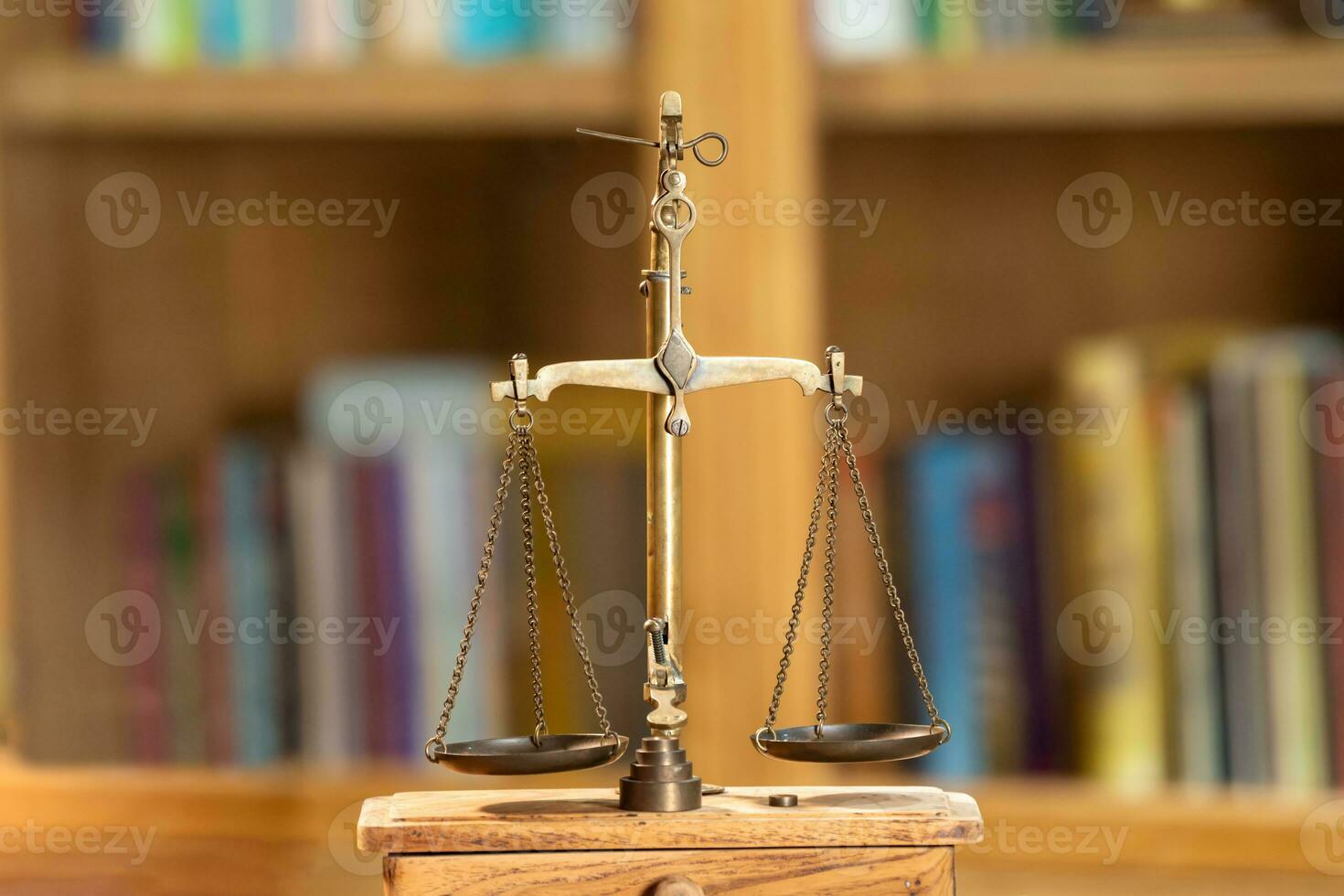 cerca arriba a dorado Clásico escala simbólico de legal y ley sección es en pie en madera base en frente de biblioteca estante. foto