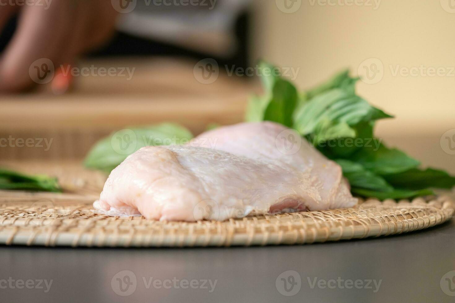 Focusing on raw a chicken is surrounded by basil, finger chilli, bergamot, eggplant ,and other Thai spicies . photo