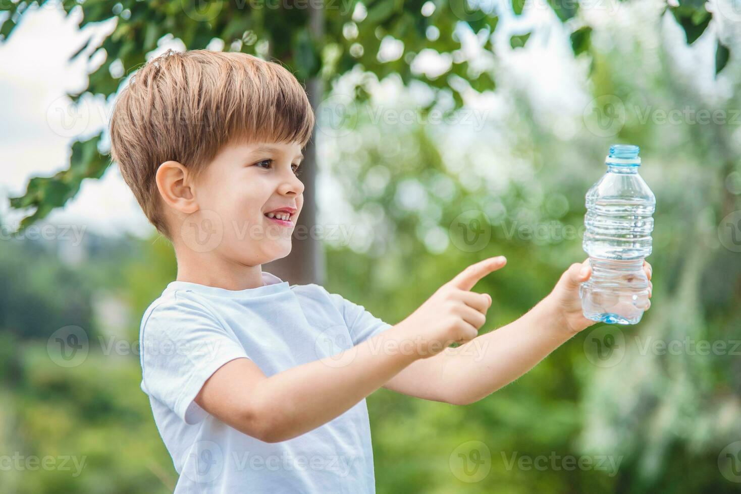 cool baby drinks clean water from a bottle on a sunny day in nature photo