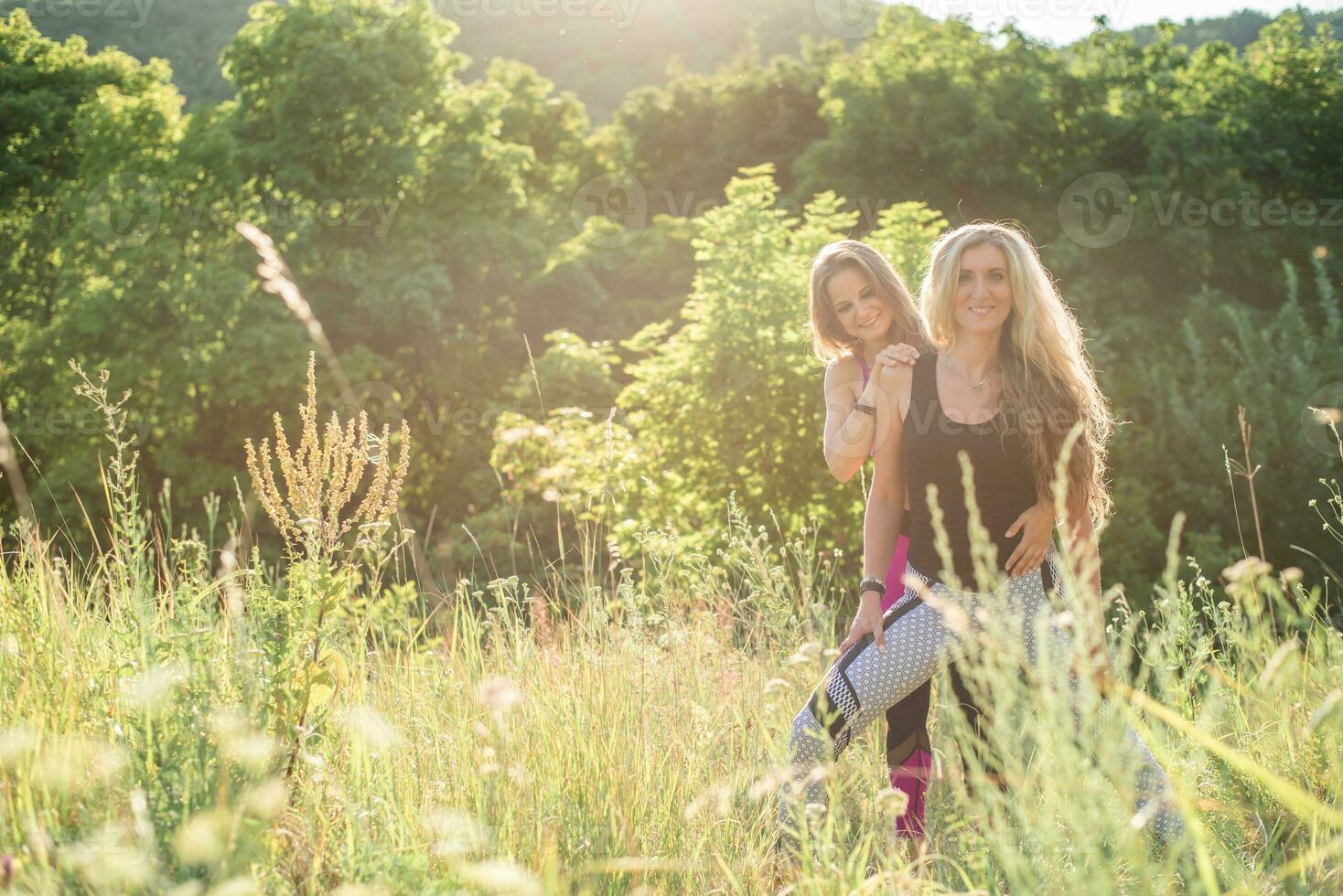 Woman yoga instructor teaching beginner in nature on a sunny day photo