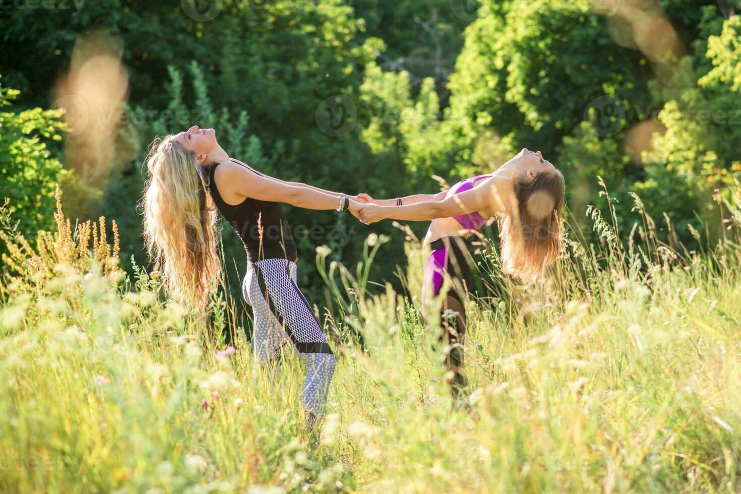 Woman yoga instructor teaching beginner in nature on a sunny day photo