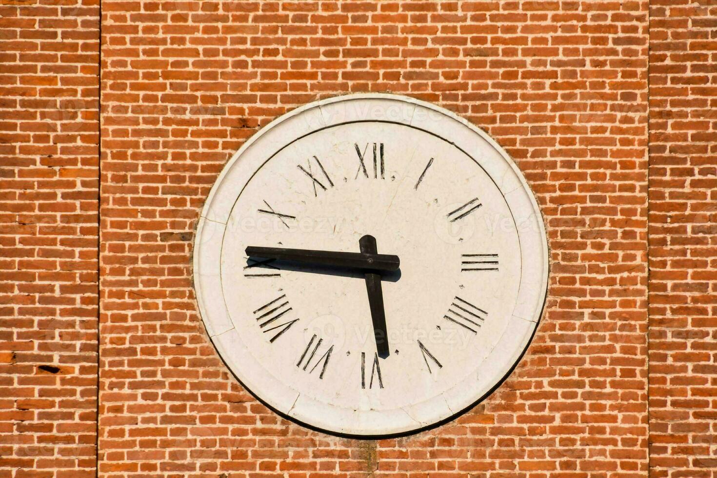 un grande reloj en un ladrillo pared con romano numerales foto