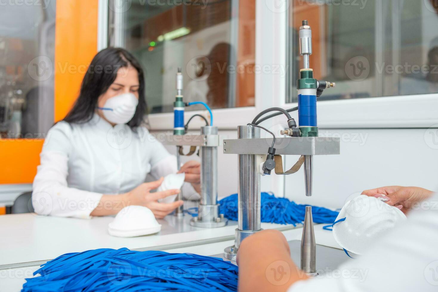 A woman works at a machine for the manufacture of medical masks with nanofibre and solder loops to them with ultrasound. Coronovirus and Covid-19 Prevention photo