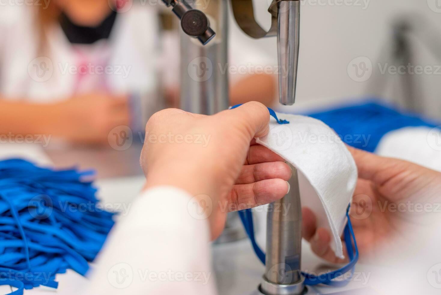 Women work at a machine for the manufacture of medical masks with nanofiber and solder loops to them with ultrasound. Coronovirus and Covid-19 Prevention photo