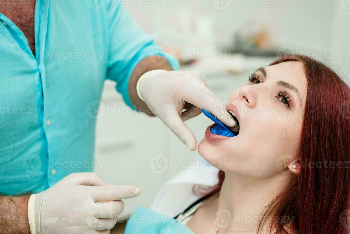The orthodontist shows the patient an impression tray in which the silicone impression material will be placed to get the shape of her teeth photo